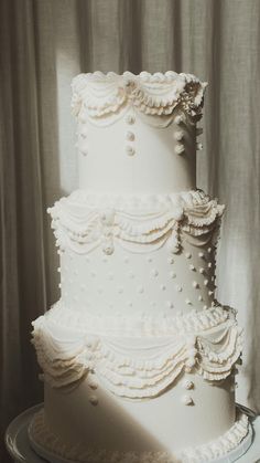 a three tiered white wedding cake sitting on top of a table