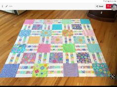 a colorful quilt is laying on the floor in front of a dresser and table top