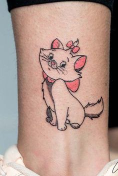 a small cartoon cat tattoo on the side of a woman's leg and ankle