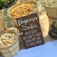 three buckets filled with popcorn sitting next to a sign that reads popcorn bar life is salty but love is sweet please feel free to take a treat