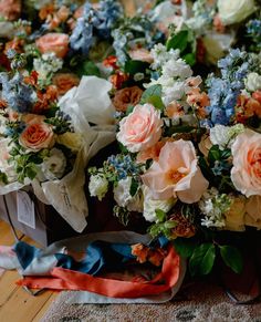 a bunch of flowers sitting on top of a wooden table next to ribbons and paper