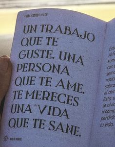 a person holding an open book in their hand with spanish writing on the front page