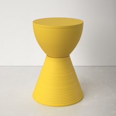 a yellow vase sitting on top of a white table next to a wall and floor