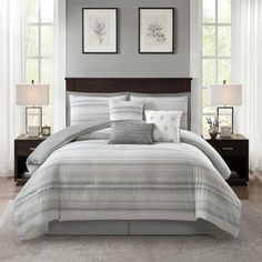 a bed with white and grey comforters in a bedroom