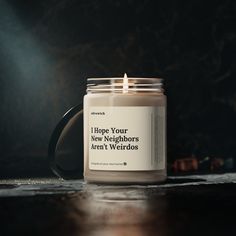 a candle is sitting on a table with a quote written in the jar and it says, i hope your new neighbors aren't weirdos