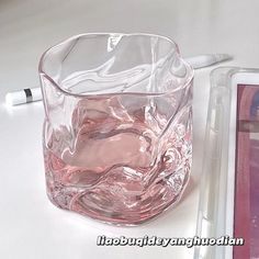 a clear glass cup sitting on top of a white table next to a notepad