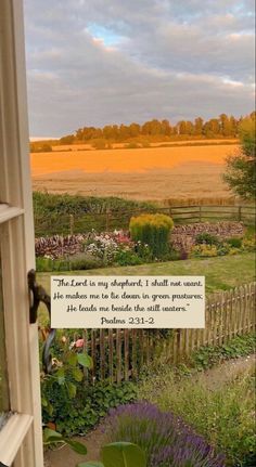 an open window with a view of a field in the distance and a bible verse written on it