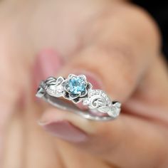 a close up of a person's hand holding a ring with a blue stone