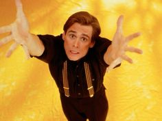 a man in black shirt and pants with hands up above his head on yellow background