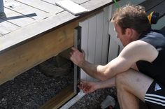 a man sitting on top of a wooden bench next to a dog house under construction