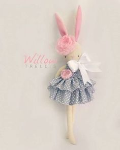 a stuffed animal with a dress and bow on it's head is posed against a white wall