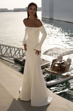 a woman in a white dress standing by the water