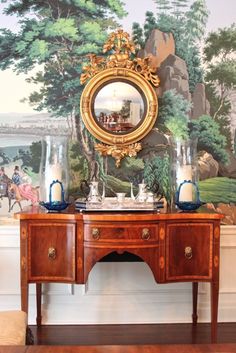 a table with a mirror on top of it next to a wallpapered mural