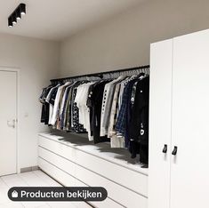 a white closet with clothes hanging on the wall