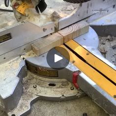 a man is using a circular saw to cut wood with a large metal object in the background