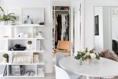 a white room with shelves and pictures on the wall next to a chair in front of a desk