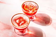 two glasses filled with liquid sitting on top of a marble counter topped with red and white substance