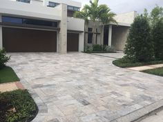 a driveway with two garages and trees in the background