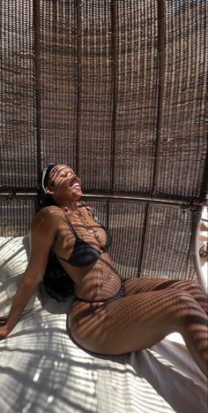 a woman laying on top of a bed next to a brown wicker wallpaper