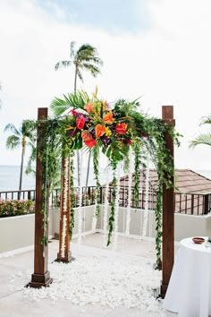 an outdoor wedding ceremony setup with flowers and greenery on the altar, overlooking the ocean