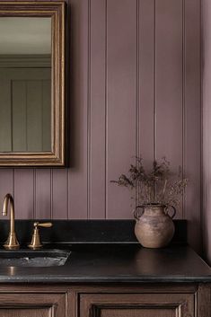 a bathroom sink sitting under a mirror next to a wooden counter top with a vase filled with flowers