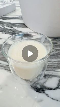 a glass bowl filled with milk sitting on top of a marble counter