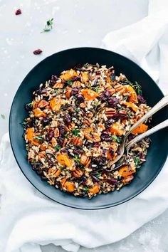 a bowl filled with rice and vegetables on top of a white cloth next to two spoons