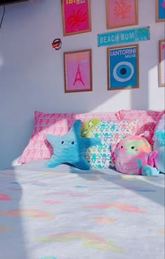 there is a bed with pink and blue pillows in the room that has pictures on the wall above it