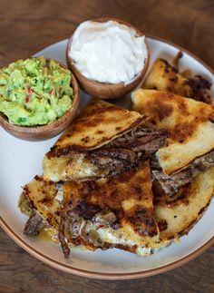 a plate with quesadillas, guacamole and sour cream