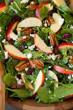 a salad with spinach, apples, cranberries and pecans