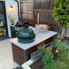 a big green egg sitting on top of a counter in the middle of a garden