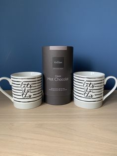 three coffee mugs sitting next to each other on a wooden table with a blue wall in the background