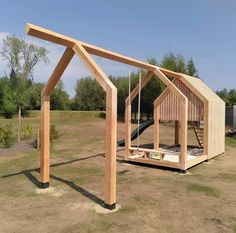 a wooden structure sitting in the middle of a field with a slide on it's side