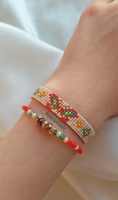 a woman's arm wearing two bracelets with beads on it and a name tag