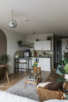 a living room filled with furniture next to a kitchen and dining room table covered in potted plants