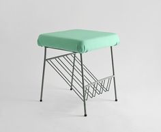 a small stool with a green seat cover on the top and metal legs, against a white background