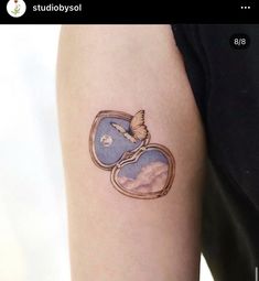 a tattoo on the arm of a woman with a bird flying over her heart shaped mirror