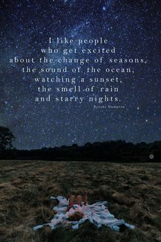 a person laying on top of a grass covered field under a sky filled with stars