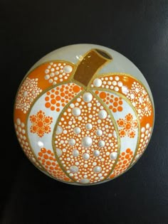 an orange and white painted pumpkin on a black surface