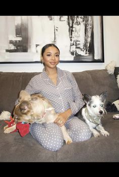 a woman sitting on a couch with two dogs