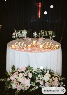 the table is decorated with flowers and gold mr and mrs signs on it's tables