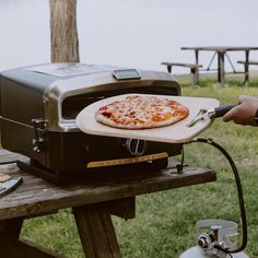 a pizza is being cooked on an outdoor grill