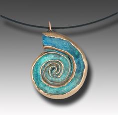 a blue and gold pendant with a spiral design on the front, hanging from a leather cord