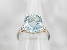 This stunning white gold ring features a beautiful aquamarine center stone with diamond accents for extra sparkle. Crafted in a classic style, this timeless piece will be a treasured part of your collection for generations to come.Metal: 18K White GoldGem: Aquamarine 4.82 CaratsGem Measurements: 9.9 x 12.0 mm, OvalAccents: 6 Diamonds totaling .10 Carats, VS-SI in Clarity, G-I in ColorRing Size: 6.75Marks: "18K JABEL" Stamped on the inside band Formal Light Blue Diamond Ring, Elegant Light Blue Aquamarine Diamond Ring, Classic Light Blue Topaz Ring For Formal Occasions, Aquamarine Brilliant Cut Diamond Ring For Formal Occasions, Formal Aquamarine Diamond Ring With Brilliant Cut, Cushion Cut Topaz Ring With Gemstone Accents For Anniversary, Formal Light Blue Diamond Ring With Center Stone, Formal Light Blue Aquamarine Diamond Ring, Aquamarine Diamond Ring With Diamond Accents