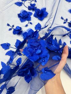 a person holding blue flowers in their hand