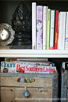 a book shelf with several books on top of it and a metal container in the middle