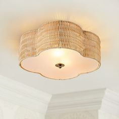 the light fixture is made out of wicker and has a white shade on it