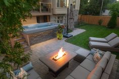 a fire pit sitting in the middle of a patio next to a building with a hot tub