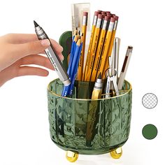 a person holding a cup full of pens and pencils with their fingers on the pen holder