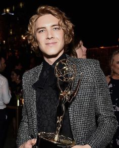 a young man holding an award in his hands at the daytime show with other people around him